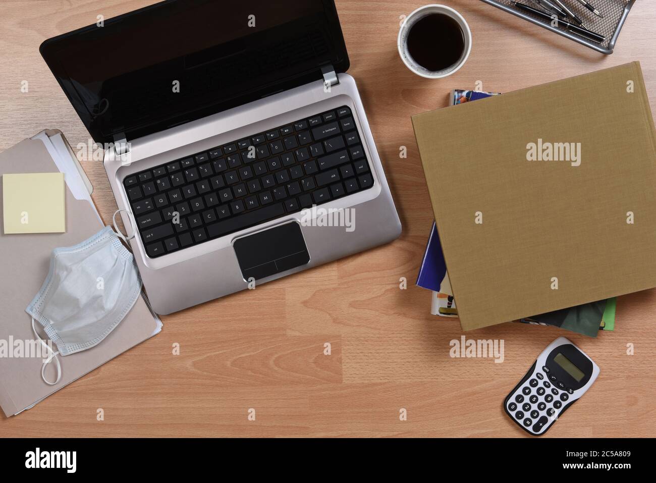 Lavorare da casa concetto. Computer portatile, cellulare, libri, caffè e altri oggetti utilizzati per il telecommuto durante il COVID-19 soggiorno a casa blocco. Foto Stock