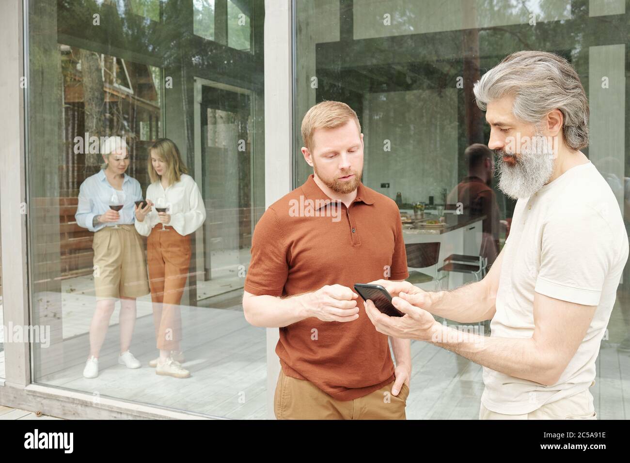 Uomo anziano che ha chiesto al figlio adulto di app per smartphone mentre parlano di tecnologia in casa Foto Stock