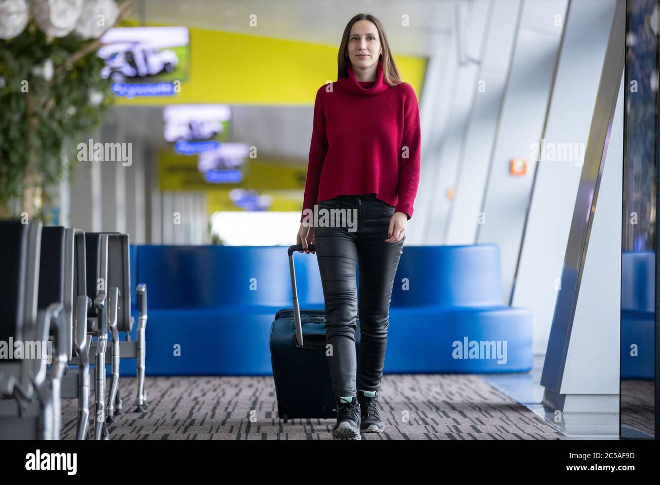 Giovane viaggiatore con il suo bagaglio a mano che cammina all'aeroporto Foto Stock