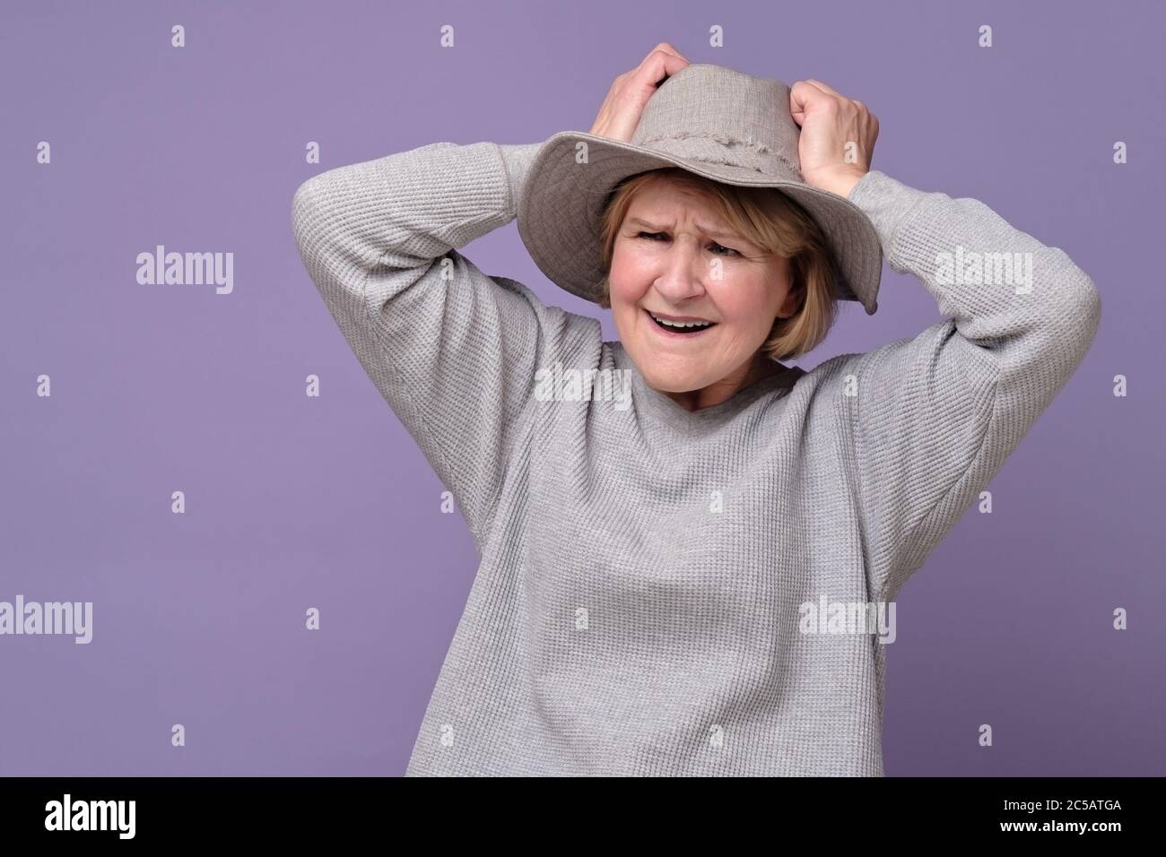 Donna caucasica anziana divertente ricordava qualcosa e tiene una mano sulla testa Foto Stock