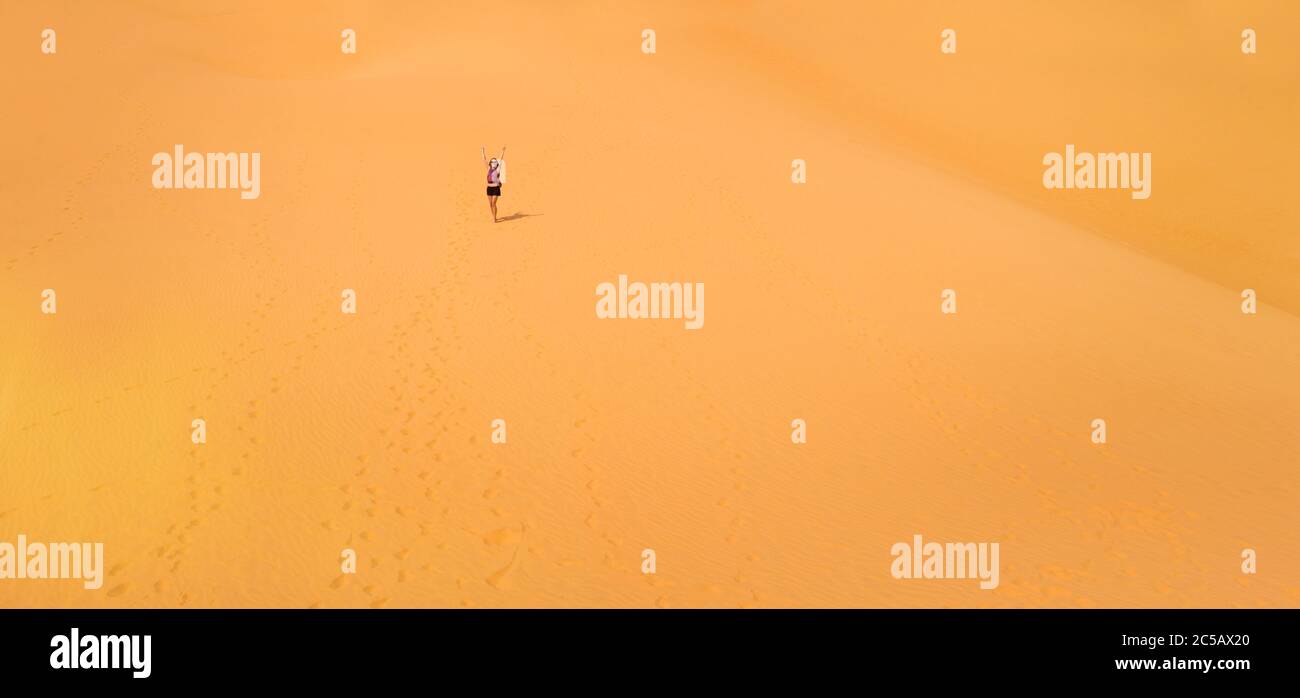 Bella ragazza caucasica che si diverte sulle dune di sabbia rossa a Mui NE, Phan Tiet zona in Vietnam. Paesaggio con cielo blu durante la giornata di sole. Foto Stock