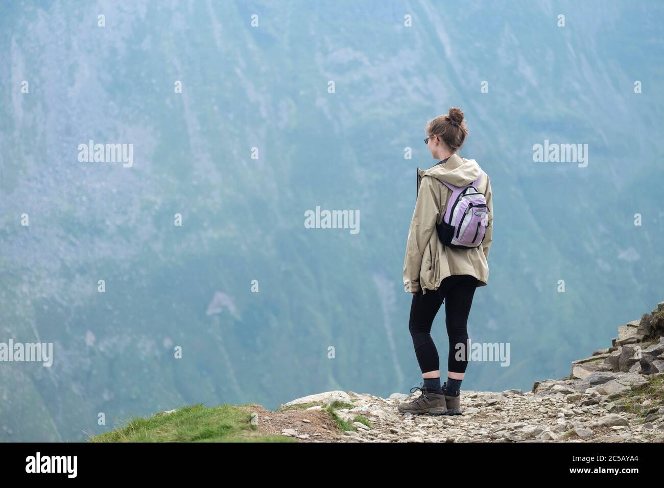Una giovane donna guarda sul bordo di Helvellyn verso Striding Edge nel Lake District Foto Stock