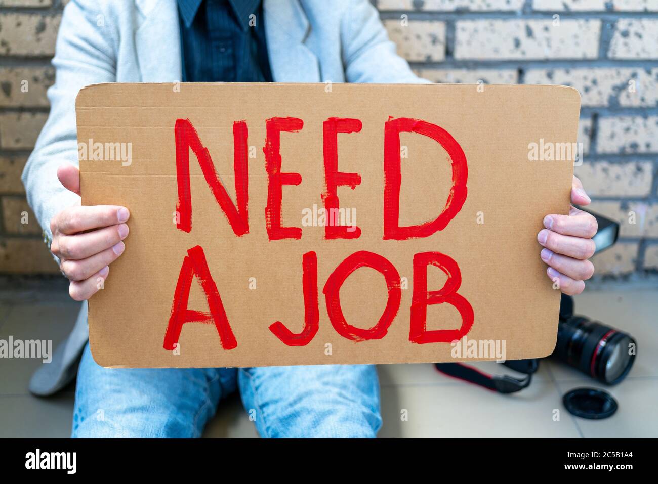 Disoccupati durante la crisi. Uomo bianco che tiene il poster nelle sue mani in cerca di lavoro. Fotografo senza lavoro. Foto Stock