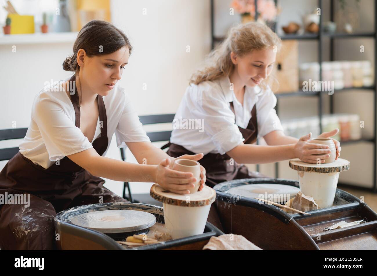 Le vaschette femmina finì di fare un vaso di argilla rimuoverlo dalla ruota del vasaio. Creazione vaso di argilla bianca. Produzione di prodotti ceramici da argilla bianca Foto Stock