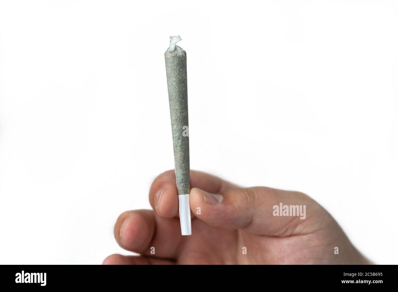 La mano maschile tiene Cannabis o Marijuana arrotolato aratura giunto o sigaretta pronto a fumare su sfondo bianco. Foto Stock