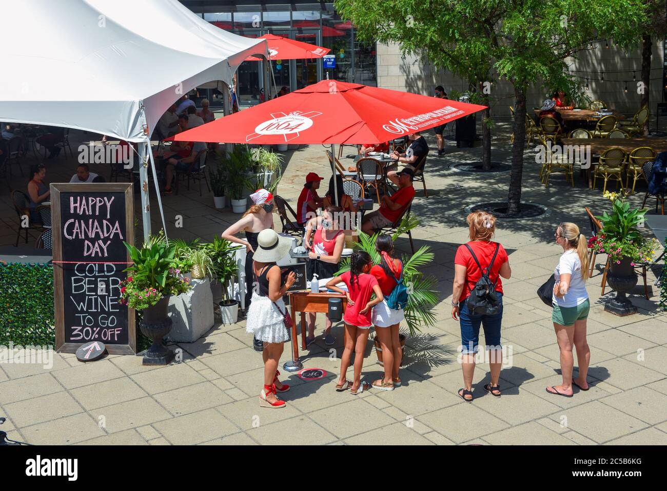 Ottawa, Canada - 1 luglio 2020: Con le celebrazioni del Canada Day annullate a causa della pandemia del Covid-19, il centro è meno affollato con persone che possono cenare solo su patii all'aperto, come questo alla Metropolitana. Un cartello offre birra e vino da andare. Foto Stock