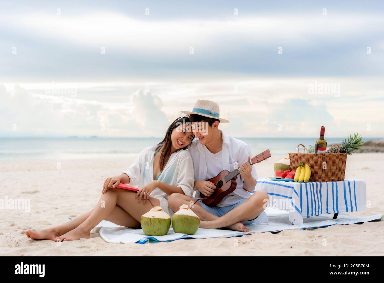 Coppia asiatica felice e godere la luna di miele viaggio di coppia amante sulla spiaggia del mare giocando Ukulele e cantando musica canzone insieme. Estate, vacanze, Foto Stock