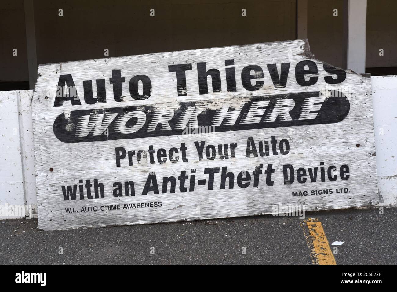 Un cartello malmenato in un parcheggio nella British Columbia, Canada avverte i conducenti che il furto di automobili è un problema nel lotto. Foto Stock
