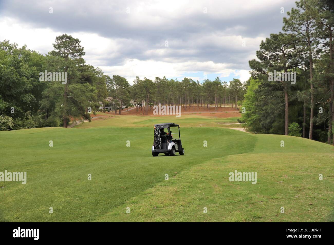 Golfer che guida un golf cart su un campo da golf splendidamente paesaggistico Foto Stock