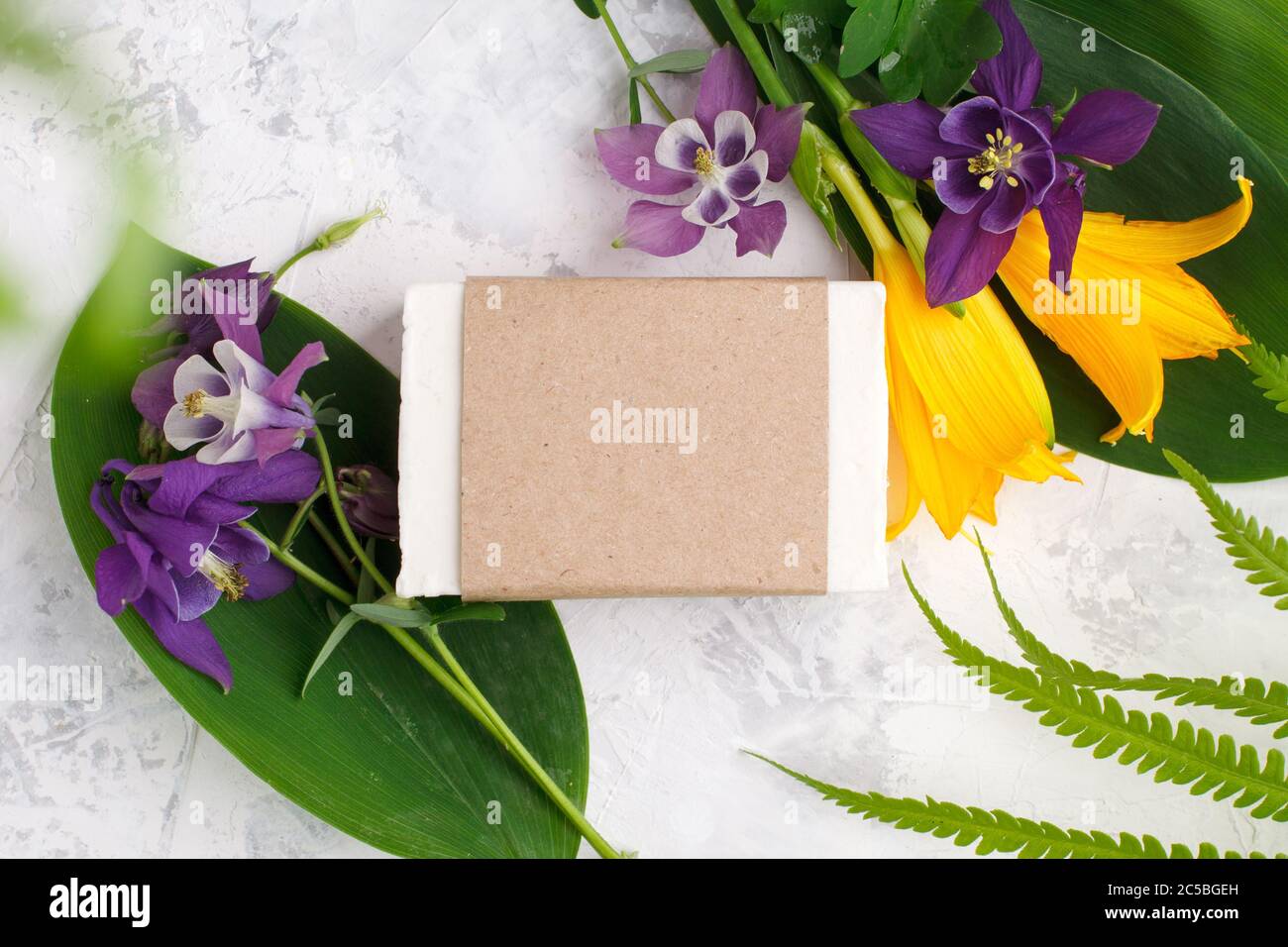 Sapone solido cosmetico o shampoo bars prodotto in artigianato, fiori su sfondo bianco. Concetto di bellezza naturale organica. Medicina di erbe, self-care messo a fuoco, Foto Stock