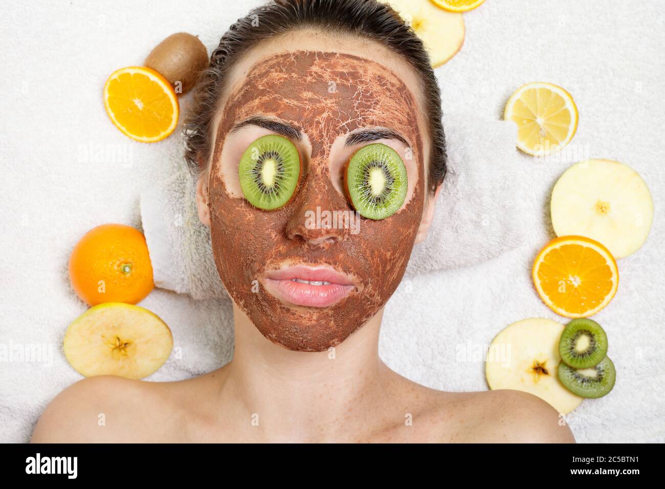 Primavera, salute, persone, gioventù e bellezza concetto -naturale frutta fatta in casa maschere facciali. Frutta fresca. Donna di cure termali che applica maschera di pulizia facciale. Bellezza T Foto Stock