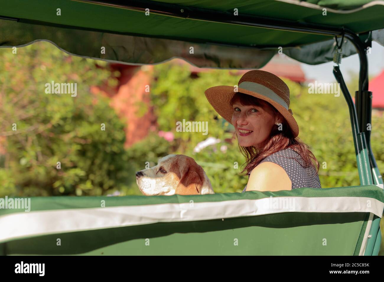Ritratto di una donna matura con il cane su una panchina nel suo giardino. Vacanza in paese. Foto Stock