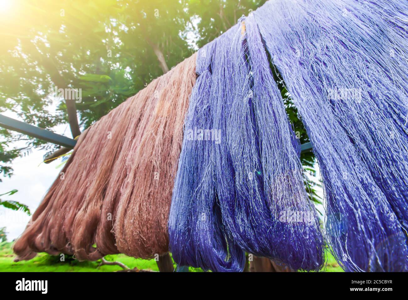 Tintura di filati di cotone con colori naturali appesi alla luce del sole per l'essiccazione, materiali naturali tradizionali, prodotti locali di Sing Buri, Thailandia. Foto Stock