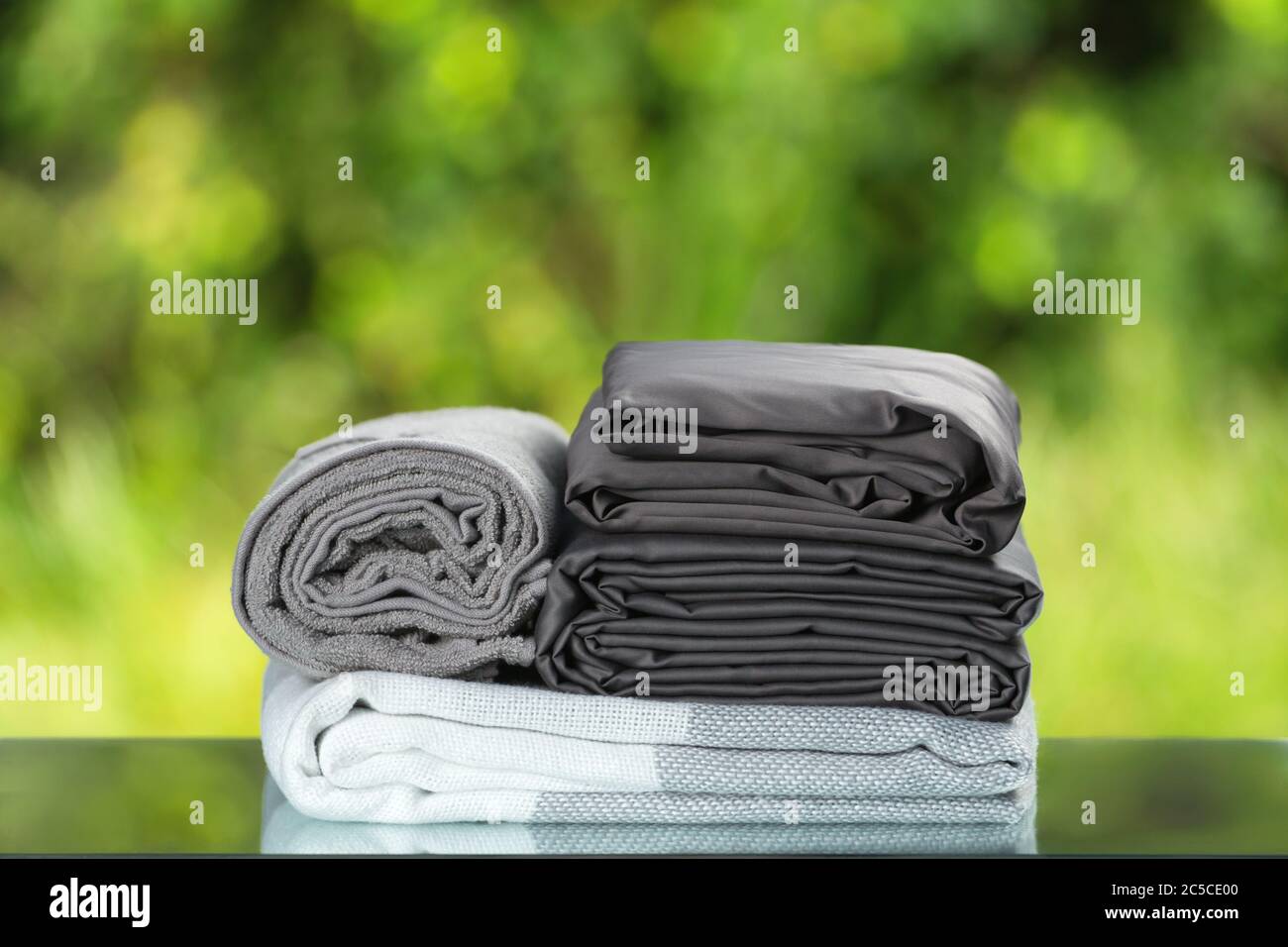 Pila di lettiere ripiegate. Set di tessuto per telo da letto grigio monocromatico su sfondo sfocato. Foto Stock