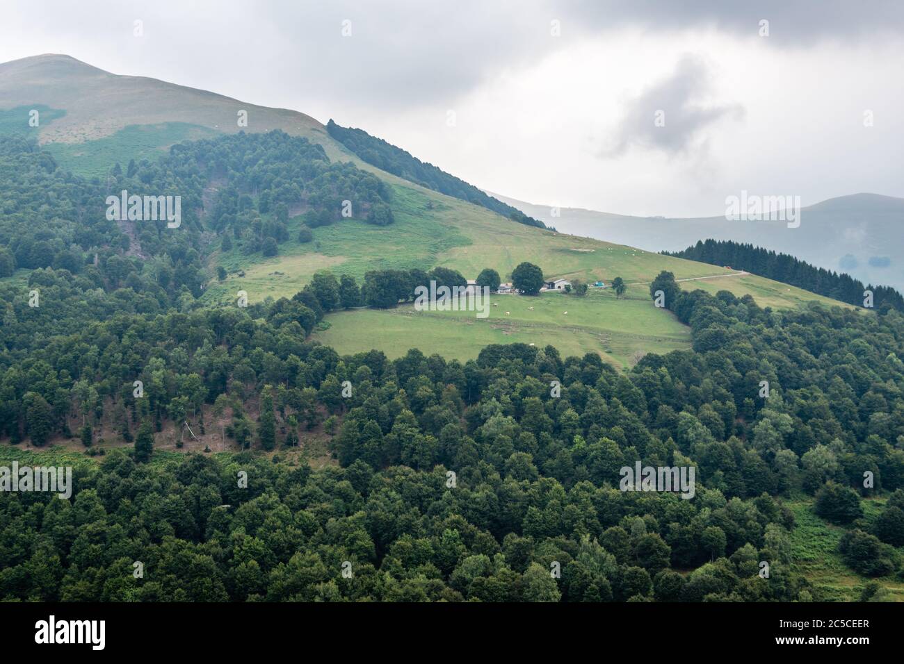 Agriturismo su una verde collina circondata da pascoli e boschi decidui, paesaggi montani della Lombardia, Italia. Foto Stock
