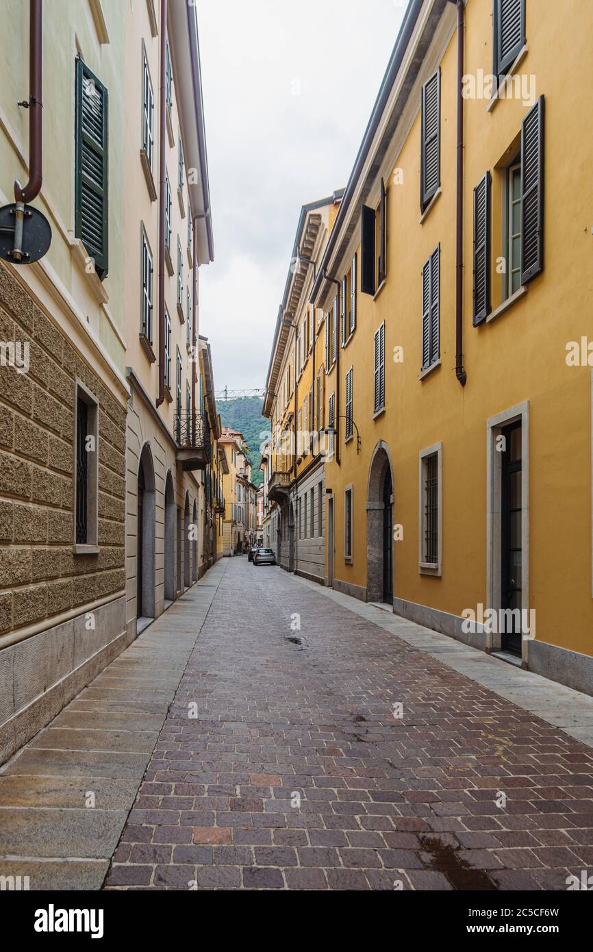 Vista su una strada stretta e vuota con facciate colorate di case a Como, Italia. Foto Stock