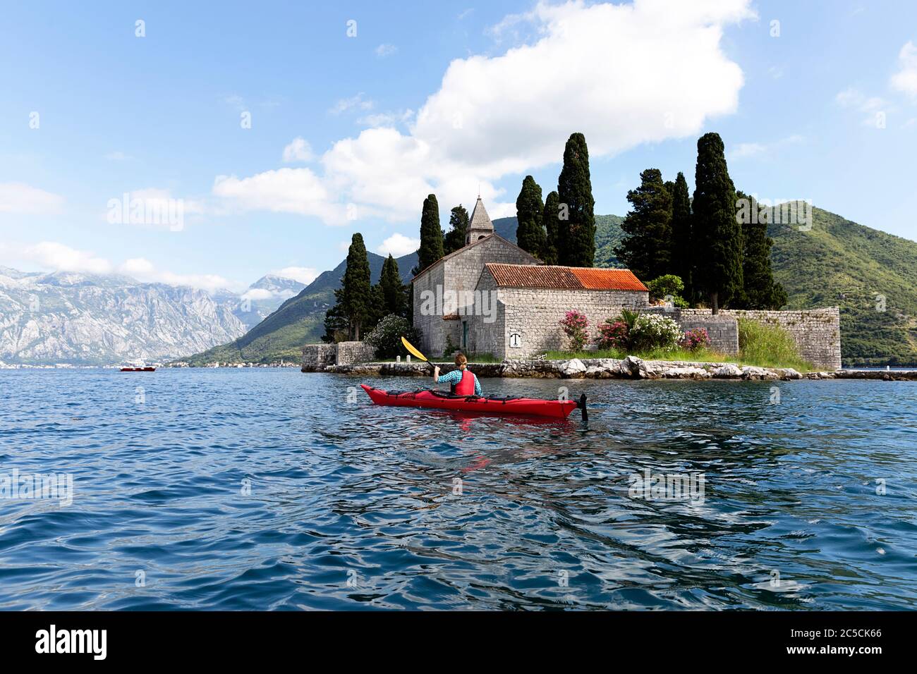 Donna kayak in kayak rosso per l'isola di San Giorgio, Baia di Cattaro, Montenegro Foto Stock