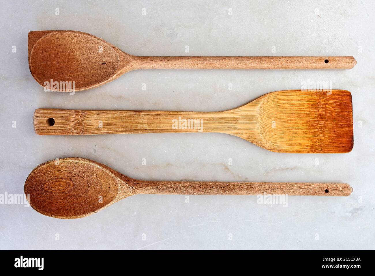 Immagine di tre cucchiai di cucina in legno su una lastra di marmo bianco. Foto Stock
