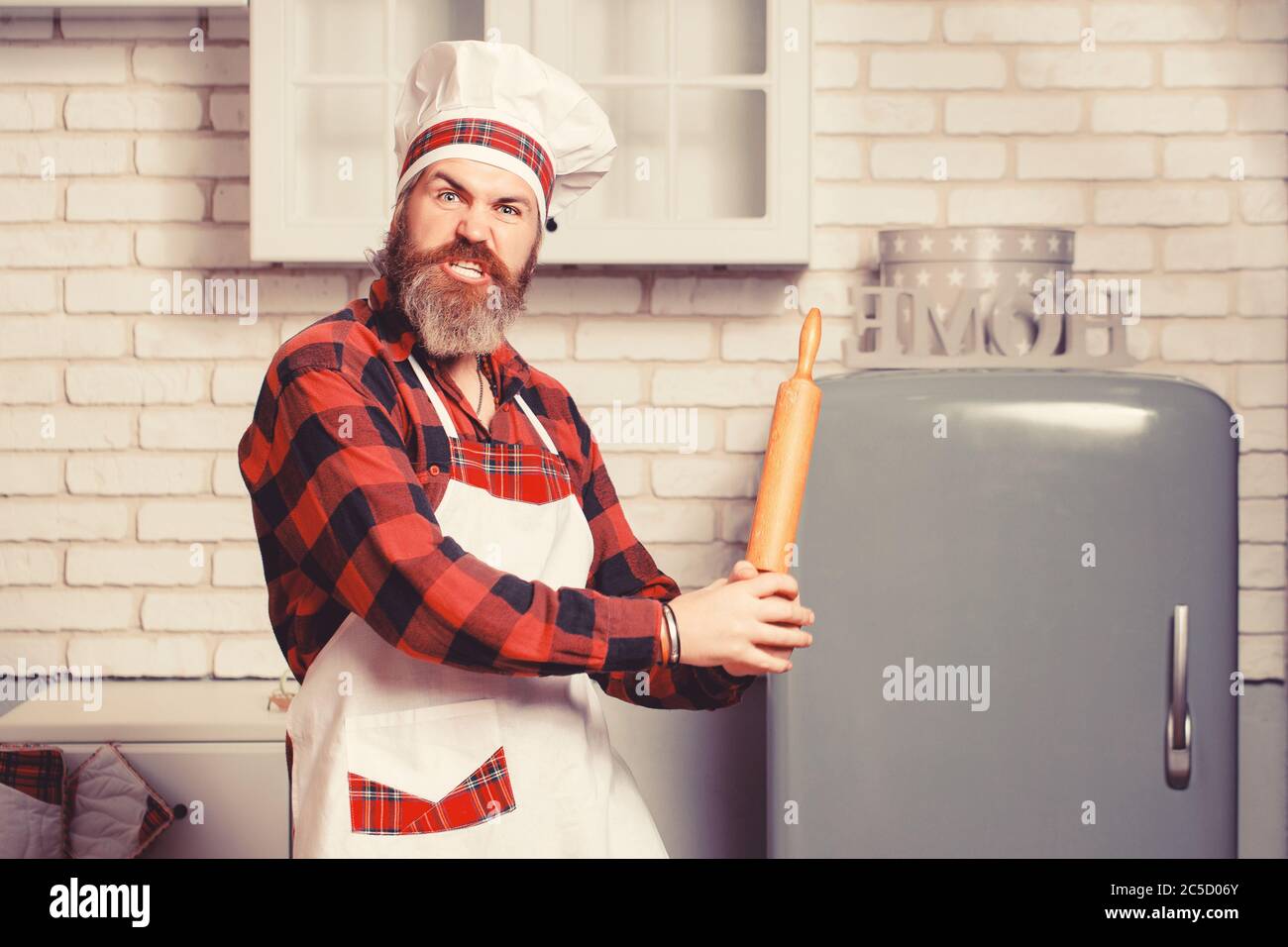 Pazzo giovane chef maschile cuoco o panettiere uomo in grembiule bianco  chefs cappello in posa in cucina sfondo Foto stock - Alamy