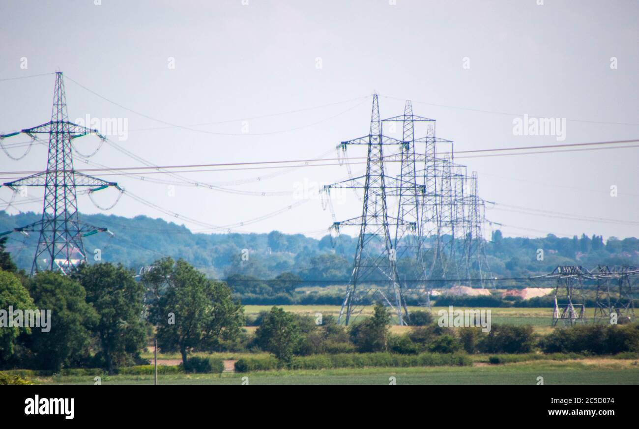 Una fila di piloni di elettricità si dipanano attraverso la campagna nel Regno Unito. Foto Stock