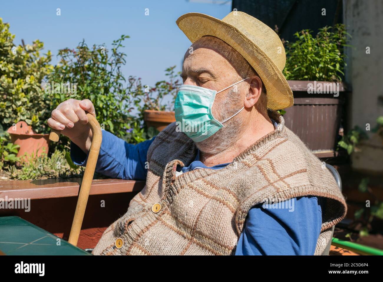 uomo anziano seduto da solo sulla terrazza durante la quarantena epidemica di coronavirus Foto Stock