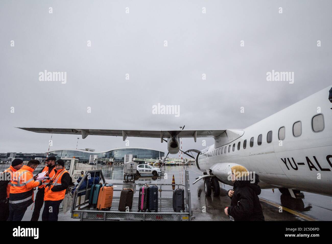 BUCAREST, ROMANIA - 11 FEBBRAIO 2020:movimentatori di bagagli che si occupano del bagaglio di un ATR 72 che è appena atterrato a Bucarest Otopeni Henri Coanda Air Foto Stock