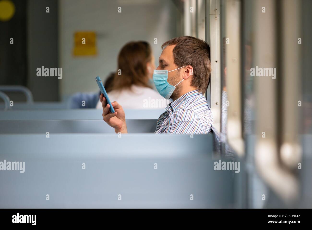 Uomo che usa smartphone, indossa una maschera protettiva in treno per proteggere il sistema respiratorio da infezione da coronavirus, covid-19. Misura preventiva. Nuovo Foto Stock