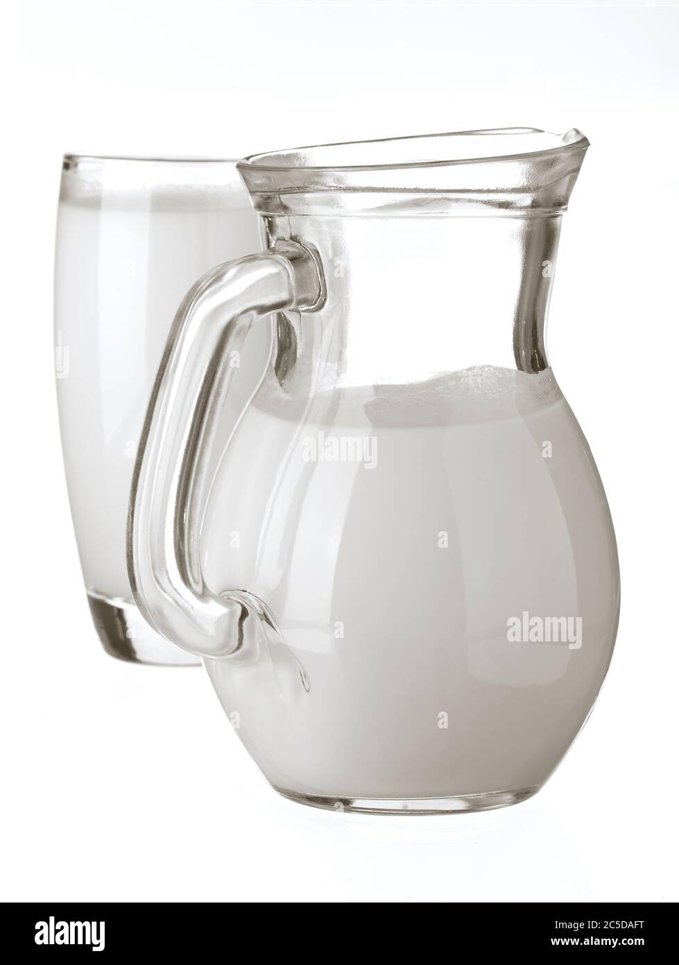 Latte intero naturale in una caraffa e un bicchiere su sfondo bianco. Primo piano, vista laterale, immagine del prodotto ad alta risoluzione. Foto Stock