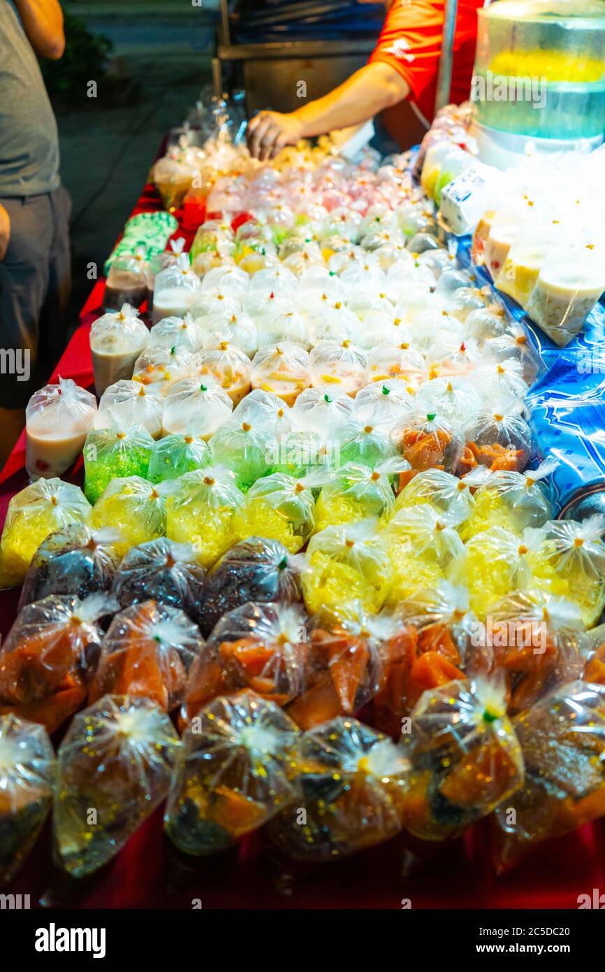 Dessert colorati in sacchetti di plastica in un mercato di Street food in Asia. Cibo asiatico insolito Foto Stock
