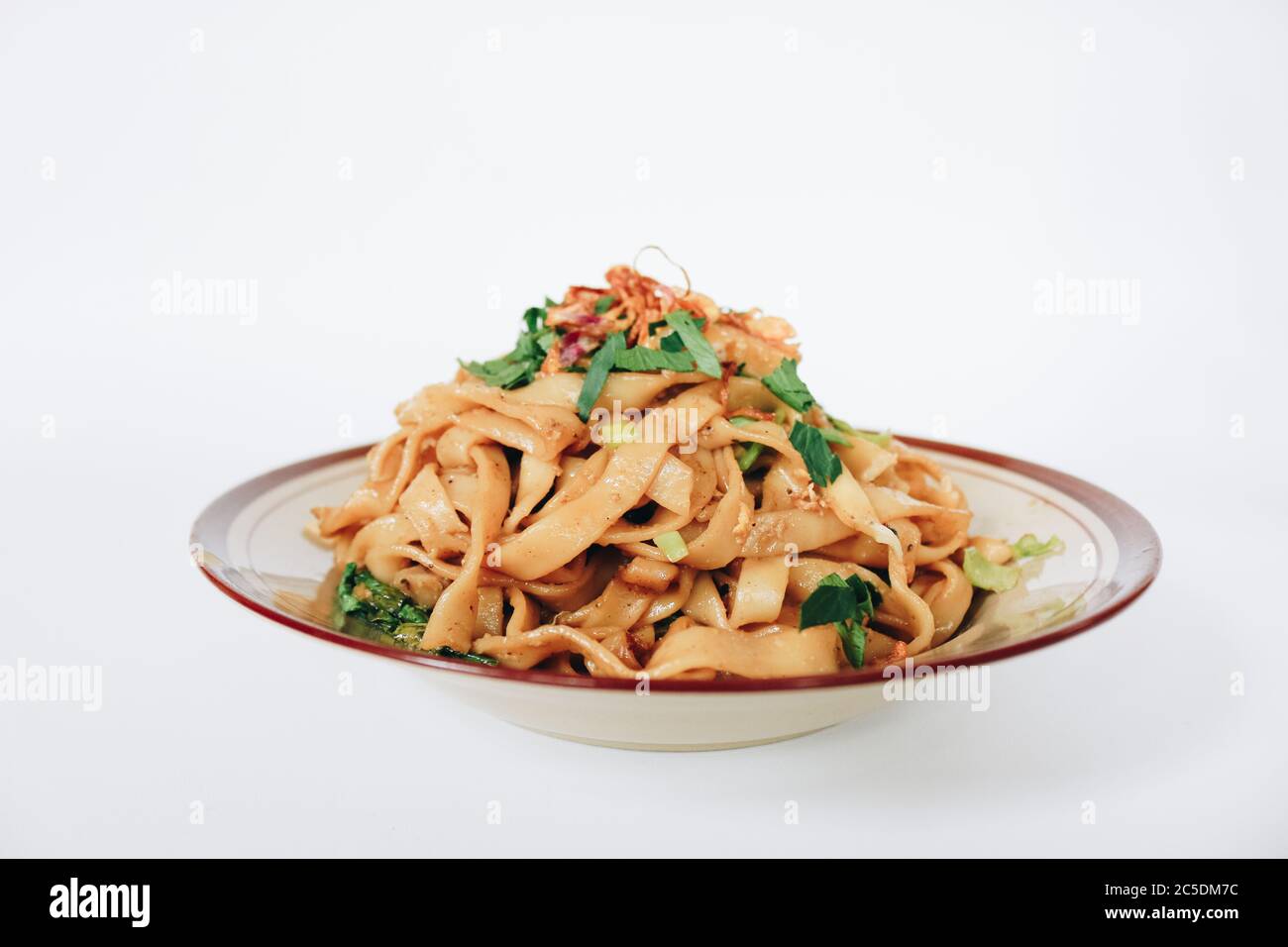 Mescolare il noodle piatto e il maiale fritti con salsa di soia scura. Indonesia ha detto chiamato Bakmie Jowo o Fried kwetiau isolato su sfondo bianco Foto Stock