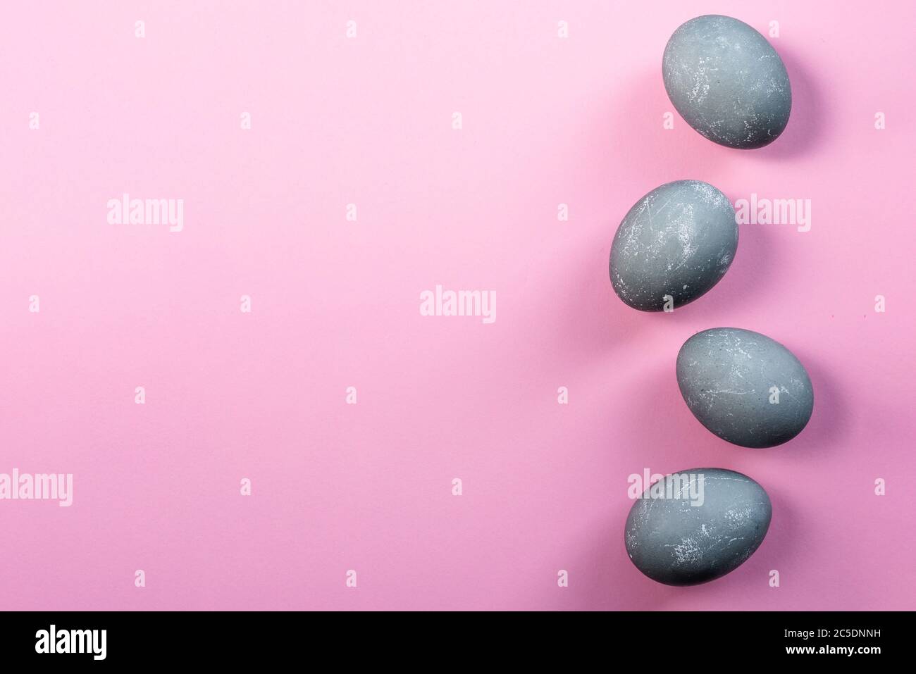 Quattro uova di pasqua a colori di cemento su sfondo rosa. Vista dall'alto, disposizione piatta. Spazio di copia. Buon concetto di Pasqua. Biglietto di auguri di Pasqua Foto Stock