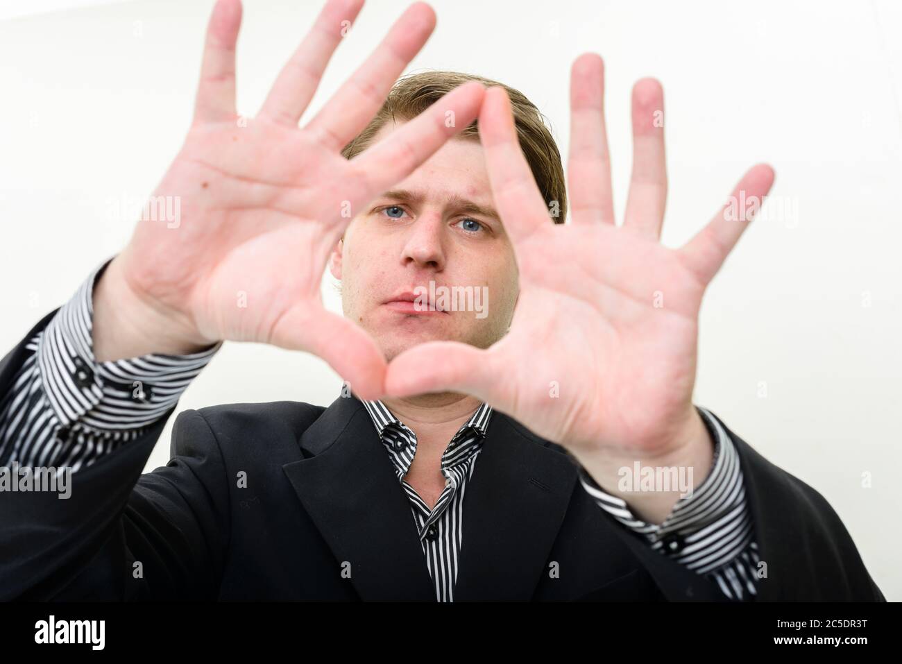 Ritratto di giovane bel uomo d'affari che mette a fuoco con le dita Foto Stock