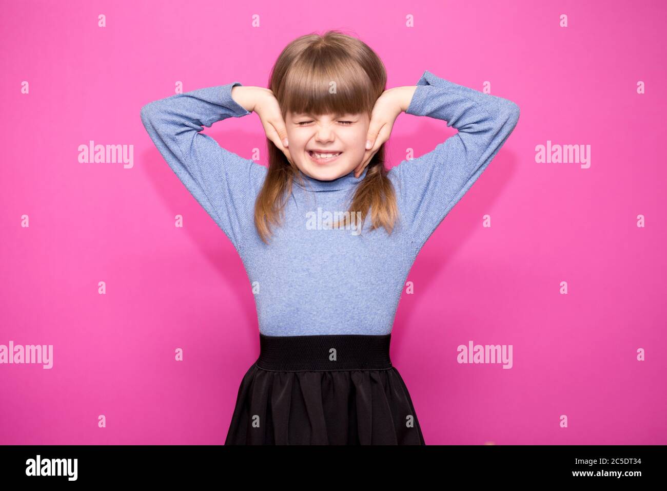 Ritratto di giovane infelice, stressata bambina che copre le orecchie con le mani che chiamano a fermare il rumore isolato su sfondo rosa Foto Stock