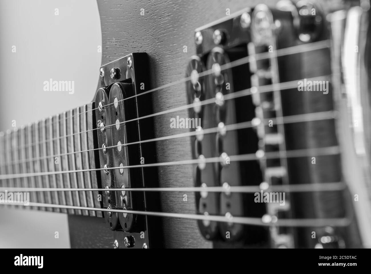 Corpo elettrico della chitarra. Strumento musicale in legno. Dettagli chitarra. Ponte di chitarra con corde. Foto in bianco e nero di una chitarra elettrica. Foto Stock