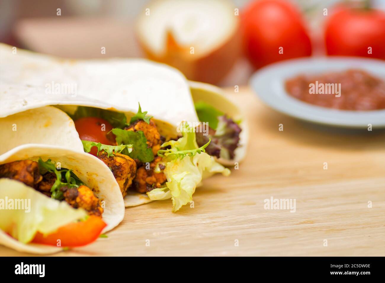 Fajita di pollo avvolge su un tavolo di legno con salsa. Foto Stock