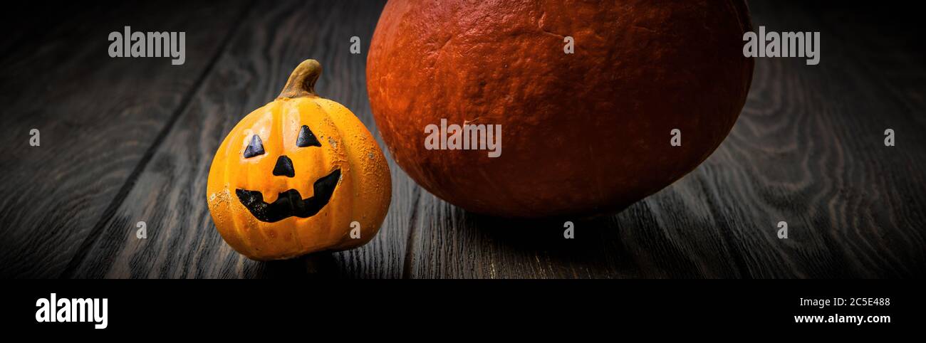 Banner orizzontale con decorazioni Halloween su un tavolo di legno scuro. Halloween sfondo con zucche. Primo piano di zucche sorridenti sulla t vintage Foto Stock