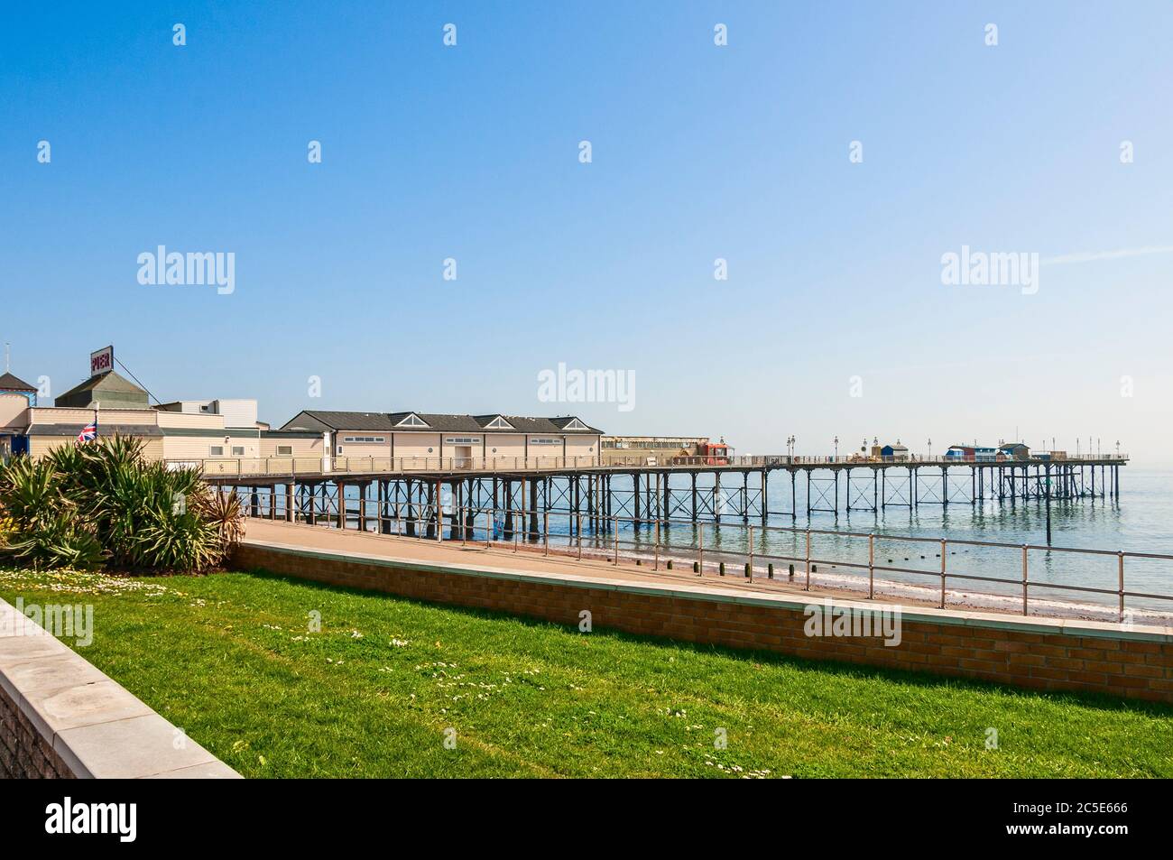 Il Teignmouth Grand Pier si estende su un mare blu verso l'orizzonte con colonne in ghisa che sostengono eleganti padiglioni e attrazioni Foto Stock