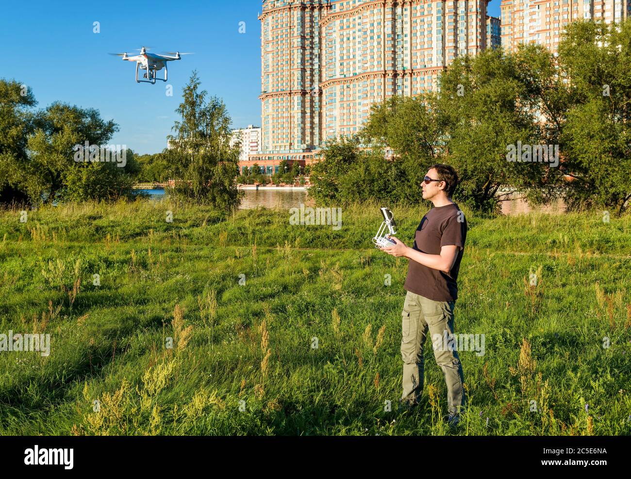 Uomo che aziona un quad copter drone con fotocamera digitale a bordo nel parco cittadino Foto Stock