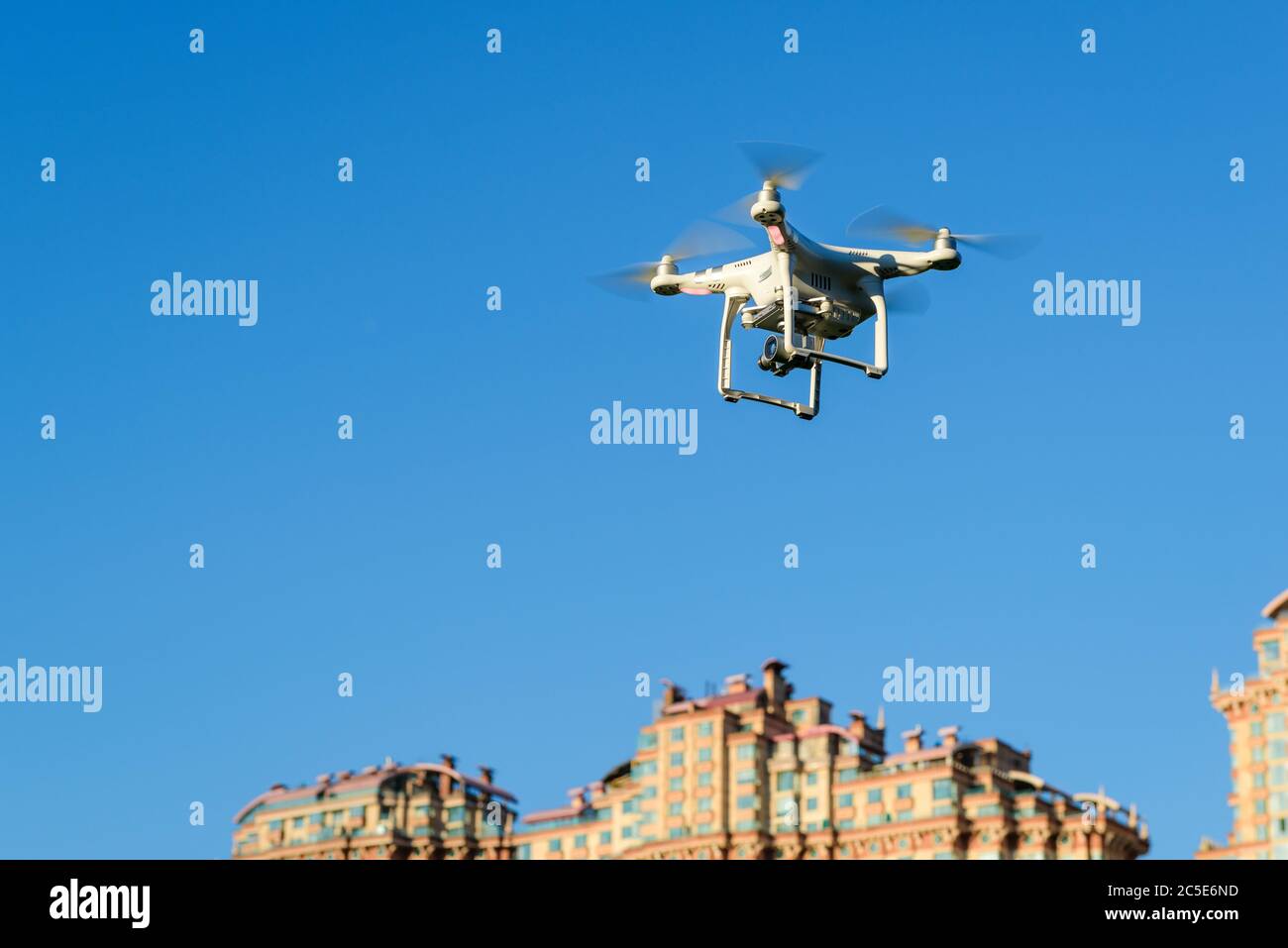 Drone quad copter con fotocamera digitale ad alta risoluzione a bordo che sorvola la città nel cielo blu. Foto Stock Drone quad copter con fotocamera digitale ad alta risoluzione a bordo che sorvola la città nel cielo blu. Foto Stock