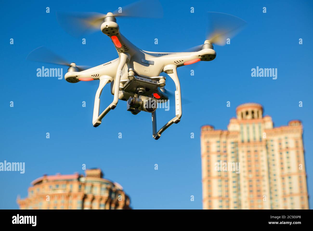 Drone quad copter con fotocamera digitale ad alta risoluzione a bordo che sorvola i grattacieli della città nel cielo blu Foto Stock
