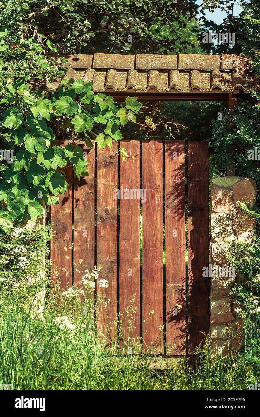Porte di legno chiuse marroni e una recinzione sovrastata da tetto di tegole verdi Foto Stock