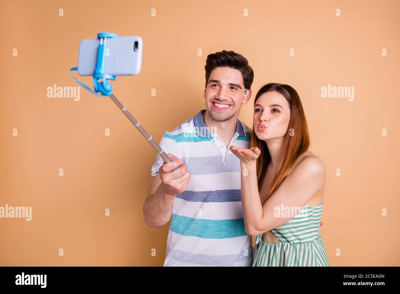 Foto di bella signora bel ragazzo coppia tenere selfie bastone fotografando inviare baci aria popolare famiglia blogger indossare casual estate vestiti isolati Foto Stock