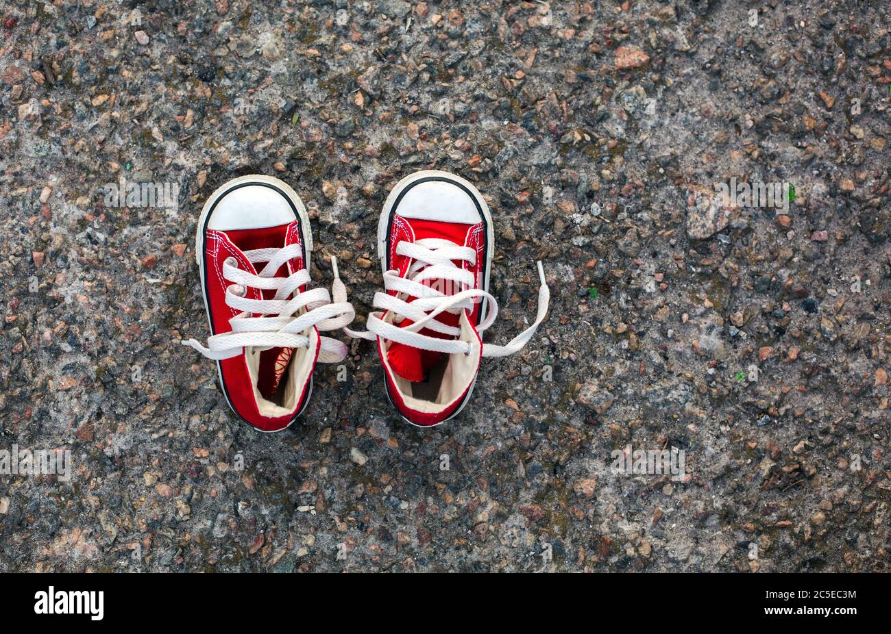 Scarpe da ginnastica rosse per bambini su fondo asfaltato Foto Stock