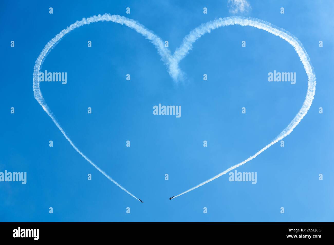 Un cuore nel cielo blu da due piccoli aerei skywriting ad uno spettacolo aereo Foto Stock