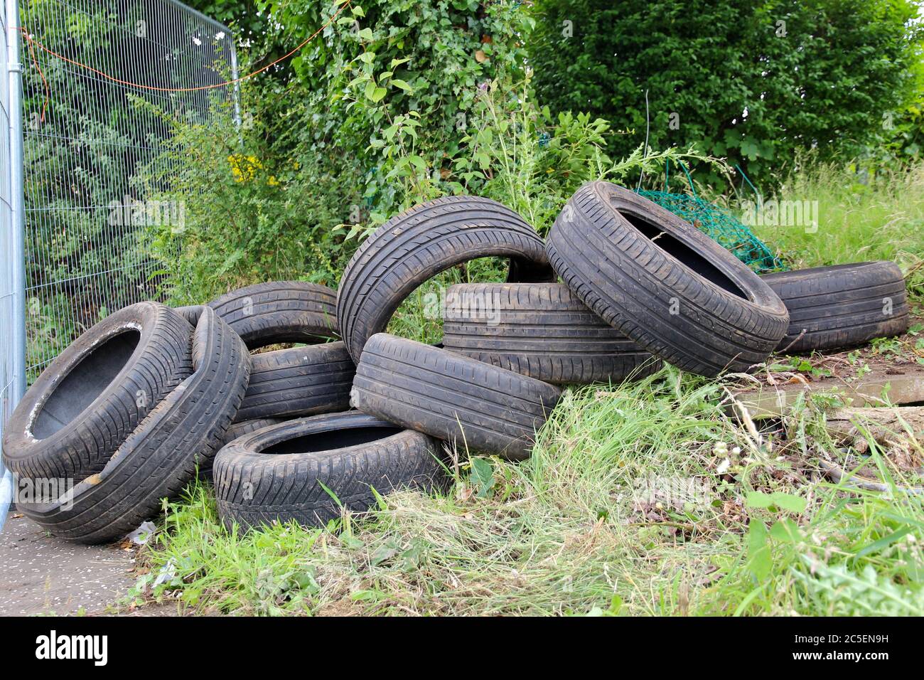 Pila di vecchi pneumatici Fly ribaltato e sinistro Littering l'erba Foto Stock