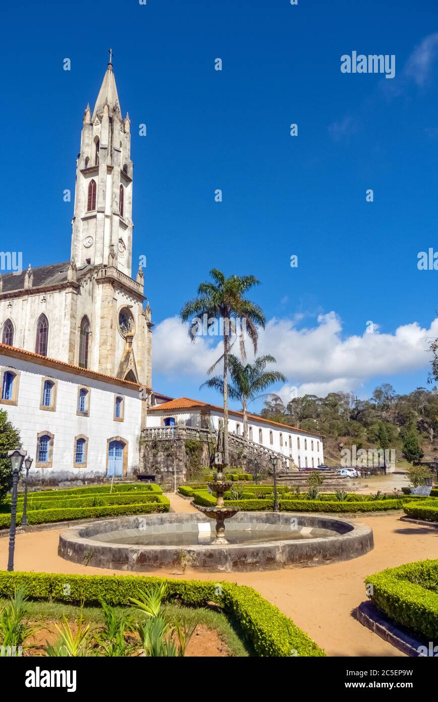 Antica chiesa neogotica e edifici laterali del complesso santuario, visto dal giardino, con cielo blu sullo sfondo, Santuario di Caraca, città di CA Foto Stock