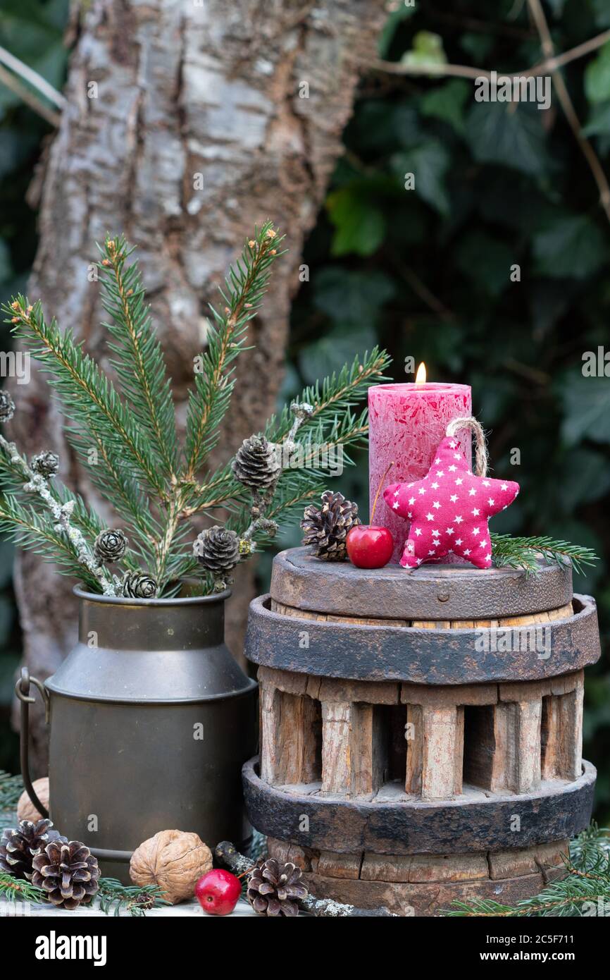 decorazione giardino invernale con candela rossa e stella di tessuto su vecchia ruota dentata Foto Stock