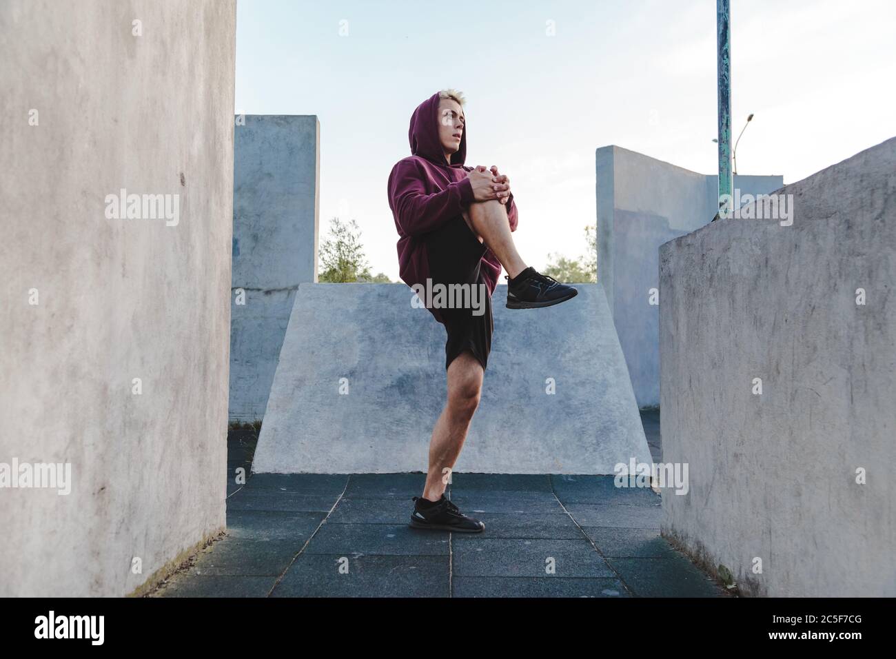 Giovane caucasico che allunga le gambe, si riscalda per correre Foto Stock