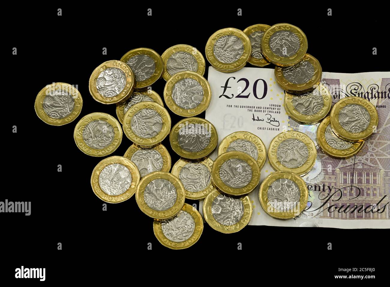 LONDRA, UK - APRILE 2019: Primo piano della valuta britannica GBP - monete da una sterlina e una nota da venti sterline isolate su un fondo nero Foto Stock