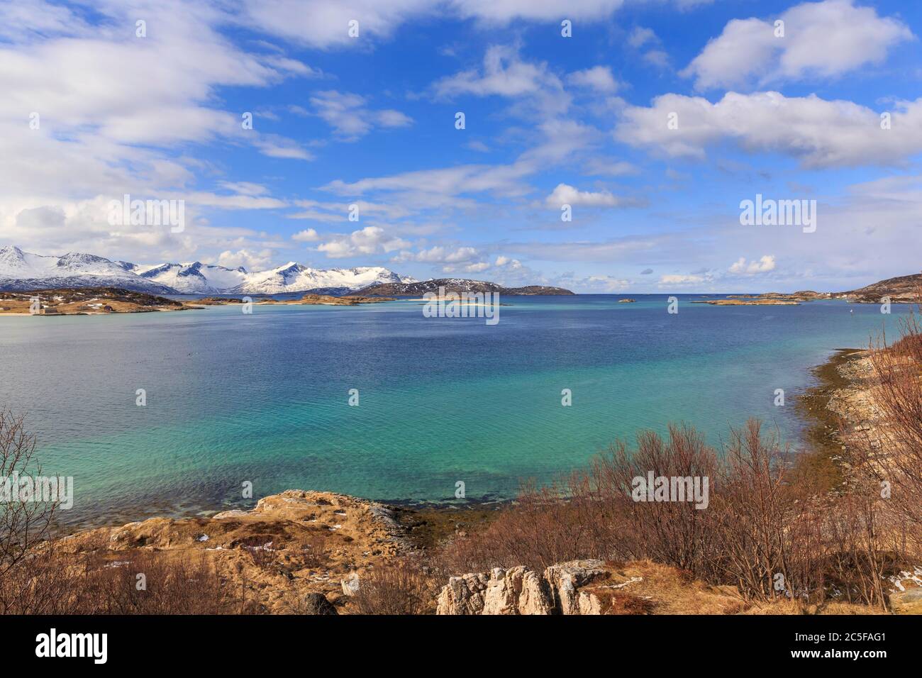 Mare turchese, dietro le montagne innevate dell'isola Senja, Sommaroysund, Sommaroy, Troms, Norvegia Foto Stock